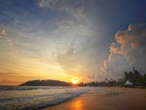 Experience the breathtaking sunset at Mirissa Beach, Sri Lanka, with vibrant skies and serene seashore.