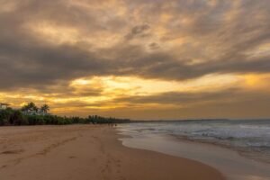 Serene sunset view over Bentota Beach and coastline in Sri Lanka, featuring golden skies and calm waves.