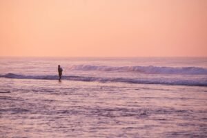 Silhouette of a person walking along Unawatuna beach during a vibrant sunset, Sri Lanka.