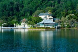 Serene view of Kandy Lake and Temple of the Tooth surrounded by lush greenery in Kandy, Sri Lanka.