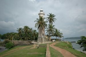 Galle Lighthouse on a scenic day with palm trees and coastal views in Sri Lanka.